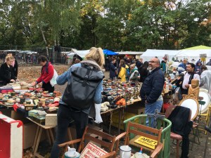 Flea market in Berlin with various stalls and people browsing items.