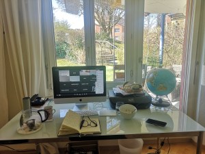 Desk with a journal and a window view of a bird feeder where birds are visiting.